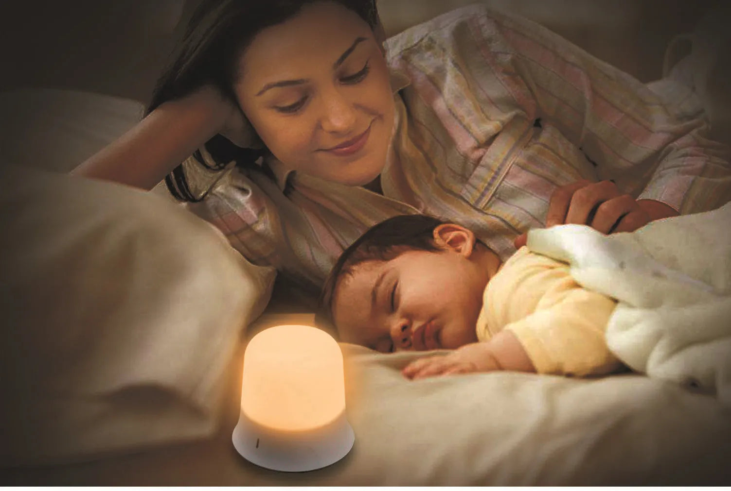 White baby night lamp with touch controls for dimming and colour change on a bedside table.