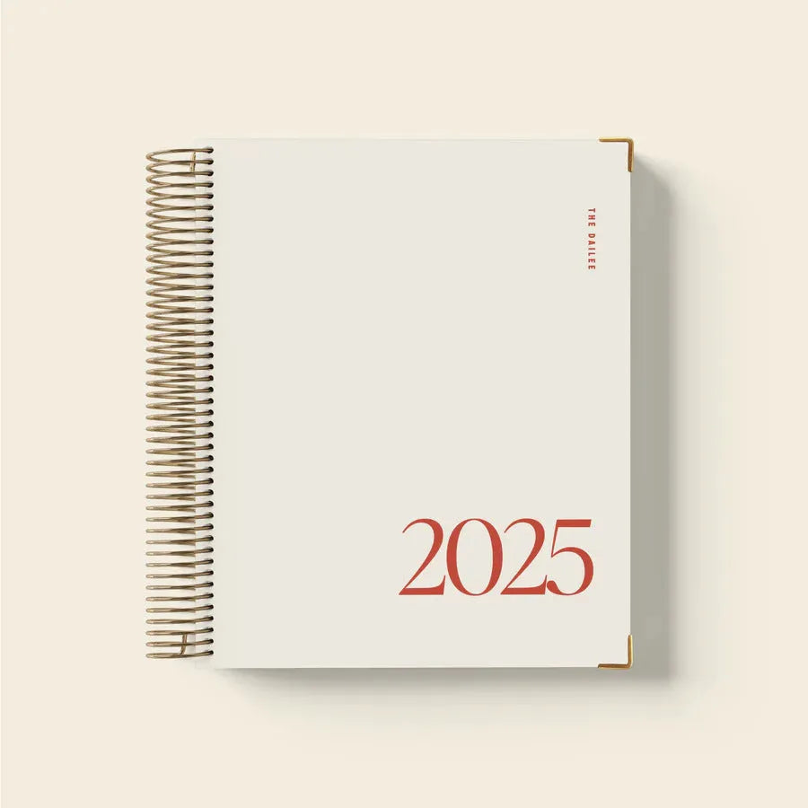 Cherry red coil-bound daily schedule notebook with wire-o binding lying open on surface