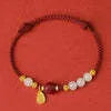 Close-up of a women's bracelet with Hetian jade and red cinnabar beads on an adjustable 925 silver chain.