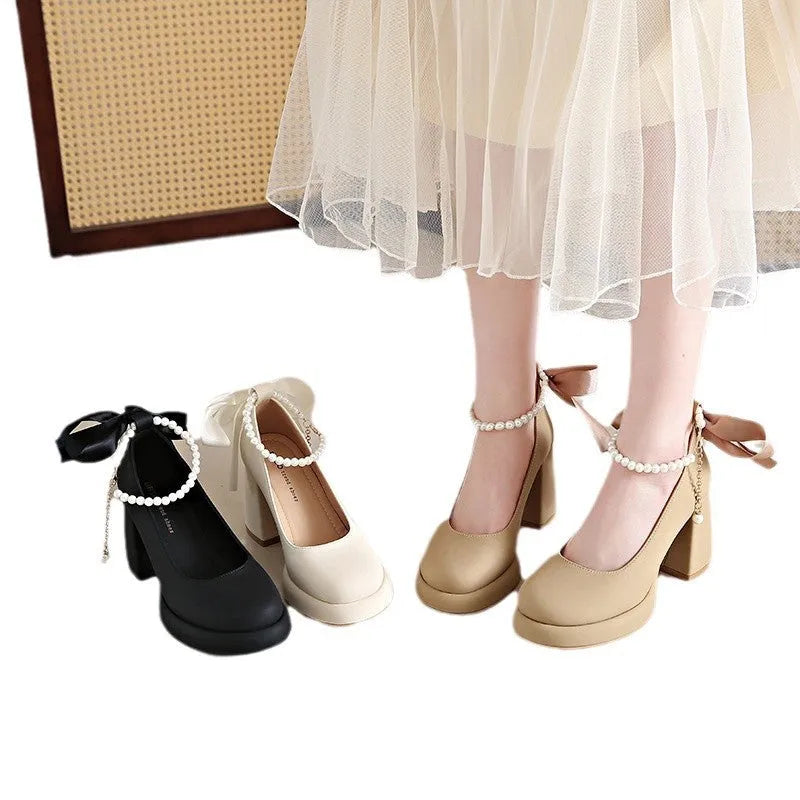 Women's beige Mary Jane shoes with a chunky heel and pearl-embellished ankle-strap buckle on a round toe.