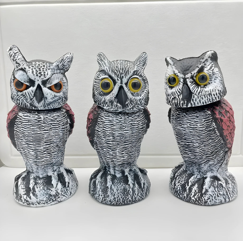 Artificial owl bird scare decoy ornament with a shaking head, shown in a garden setting.