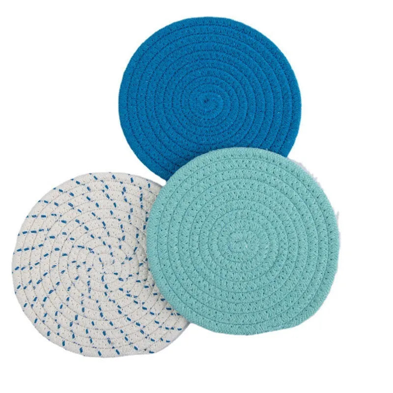 Three round grey cotton cord coasters arranged on a wooden table.