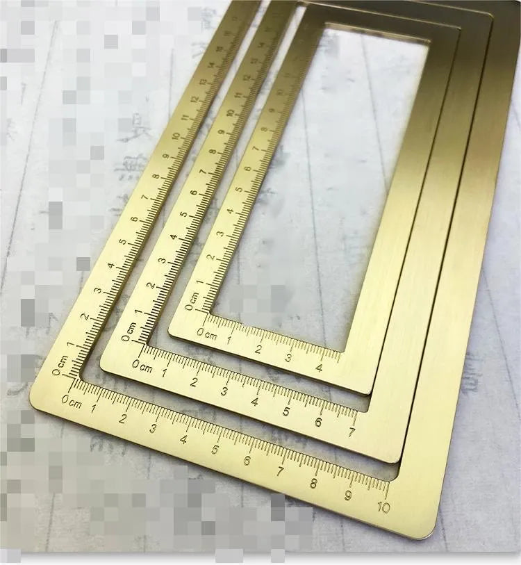 Square solid brass calligraphy paperweight with carved scale design on a wooden desk.