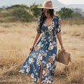 Yellow floral print summer dress on a woman, showing V-neck, short sleeves, elastic waist, and a flowing mid-length skirt.
