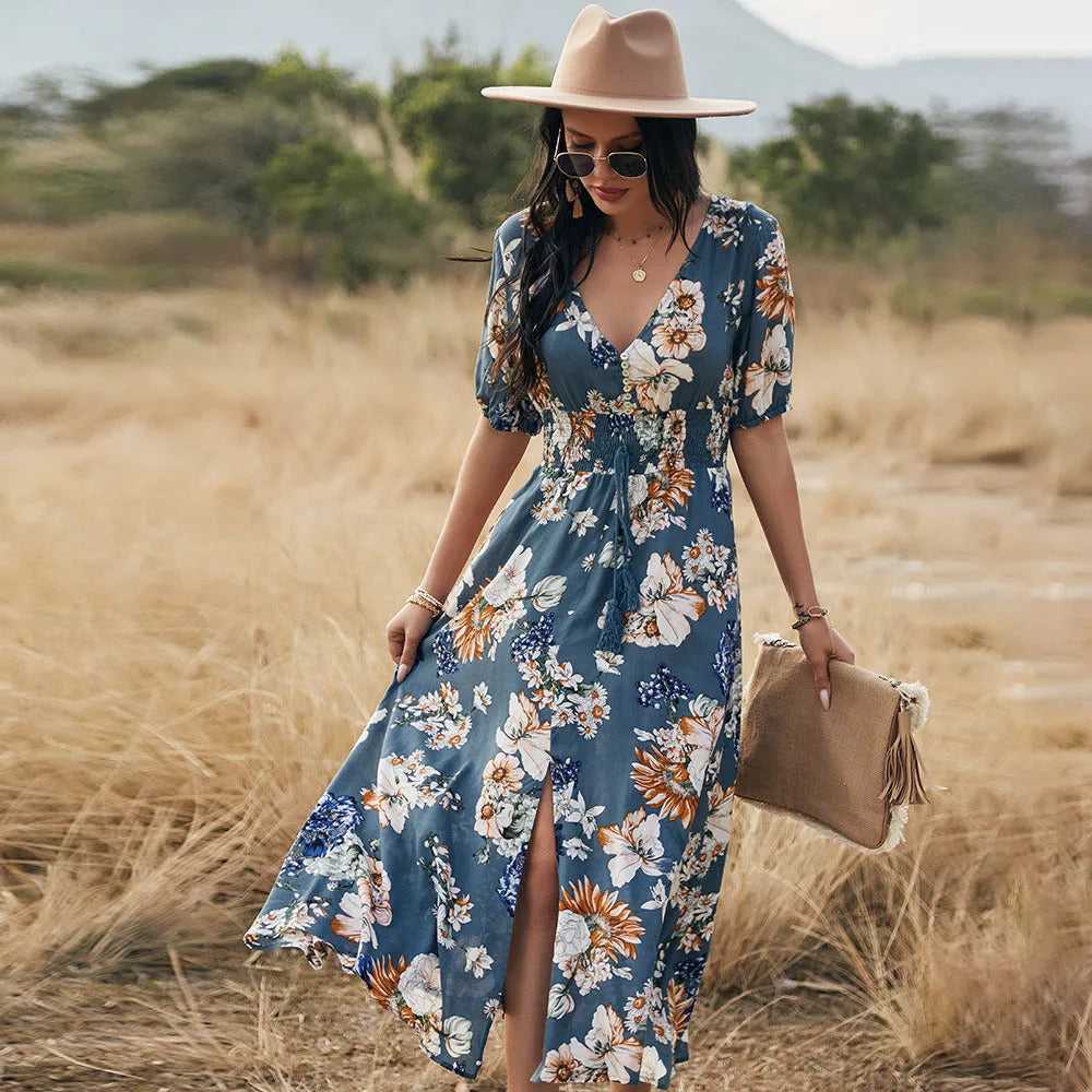 Yellow floral print summer dress on a woman, showing V-neck, short sleeves, elastic waist, and a flowing mid-length skirt.
