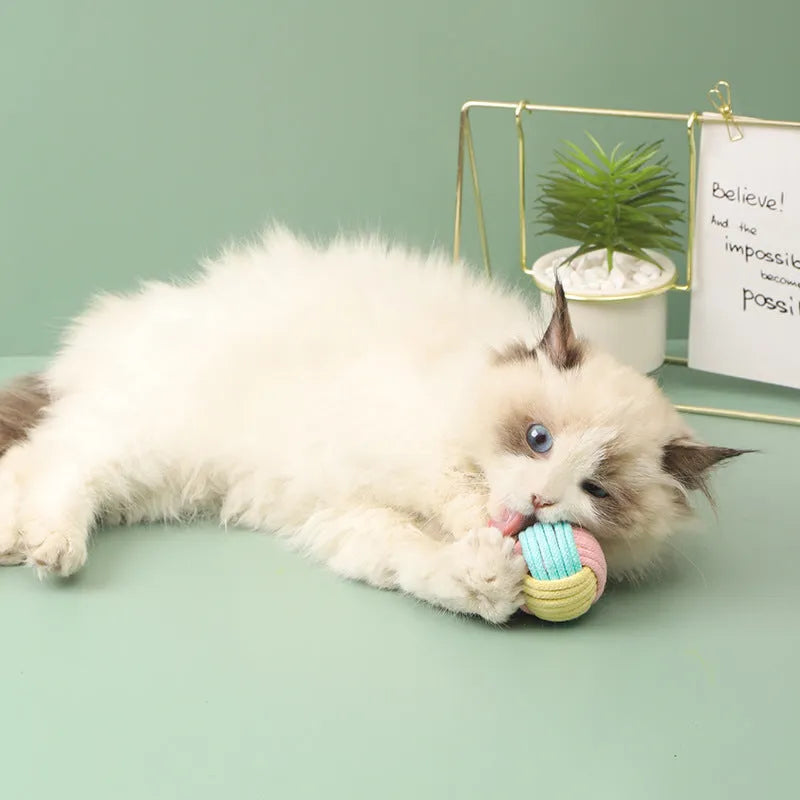 Four small handmade cotton plush balls for cats in assorted two-tone colours, shown next to a ruler for scale.