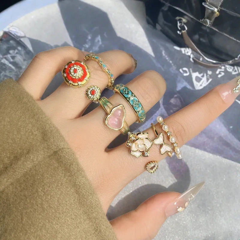 Adjustable copper ring with vintage oil dripping finish showing gourd, flower and bow design with inlaid zircon stones.