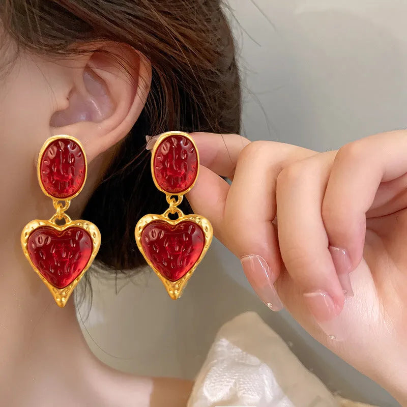 A pair of silver needle pleated oval love heart stud earrings in alloy metal, showing the textured surface and heart shape.