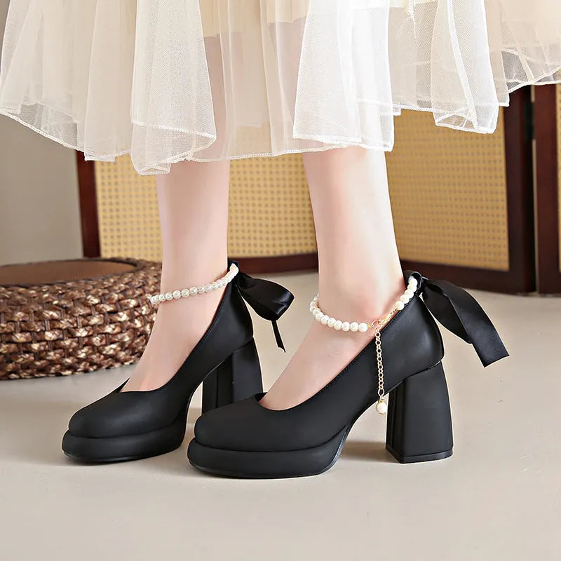 Women's beige Mary Jane shoes with a chunky heel and pearl-embellished ankle-strap buckle on a round toe.