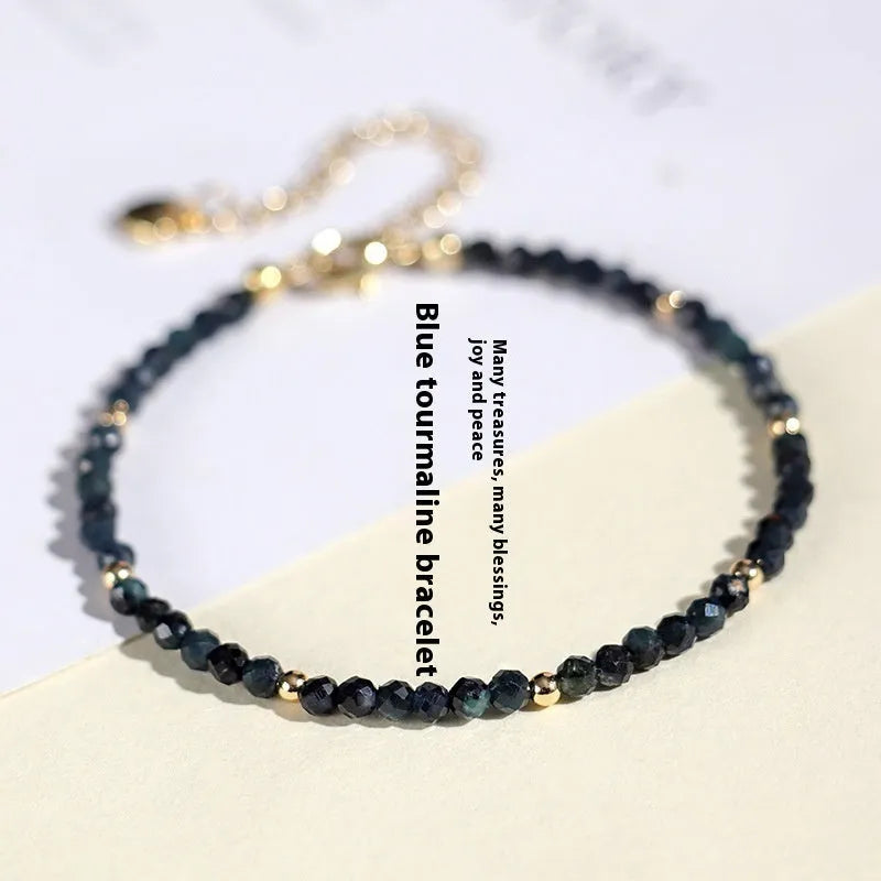 3mm blue tourmaline cut bead bracelet with gold spacer beads on wrist
