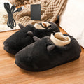 A pair of black USB electric heating slippers with a soft velvet upper and a USB cable connected to the heel.
