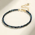 3mm blue tourmaline cut bead bracelet with gold spacer beads on wrist