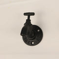 Metal water pipe style towel rack hook in modern design mounted on a wall.