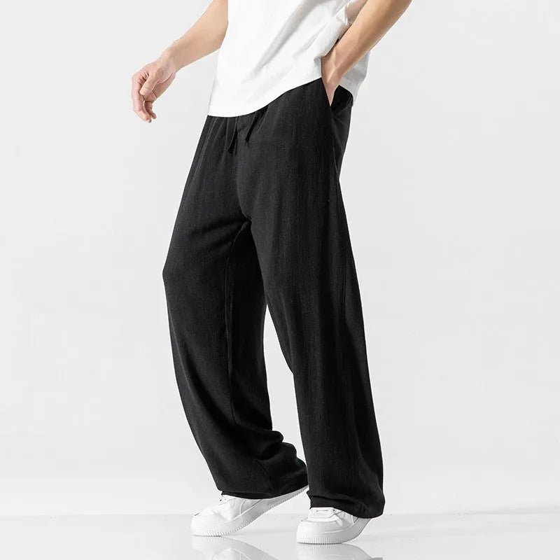 Man wearing beige straight-leg cropped linen trousers with a drawstring waist.