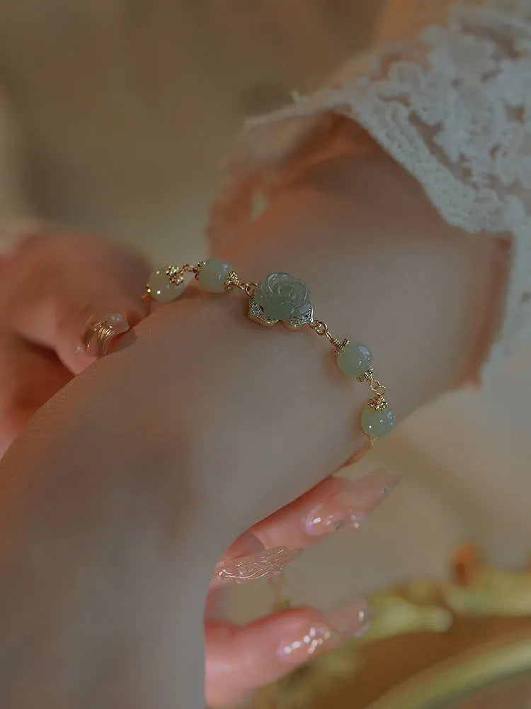 Close-up of a women's bracelet with a handmade Hetian Jade rose flower on a 14K gold plated band.