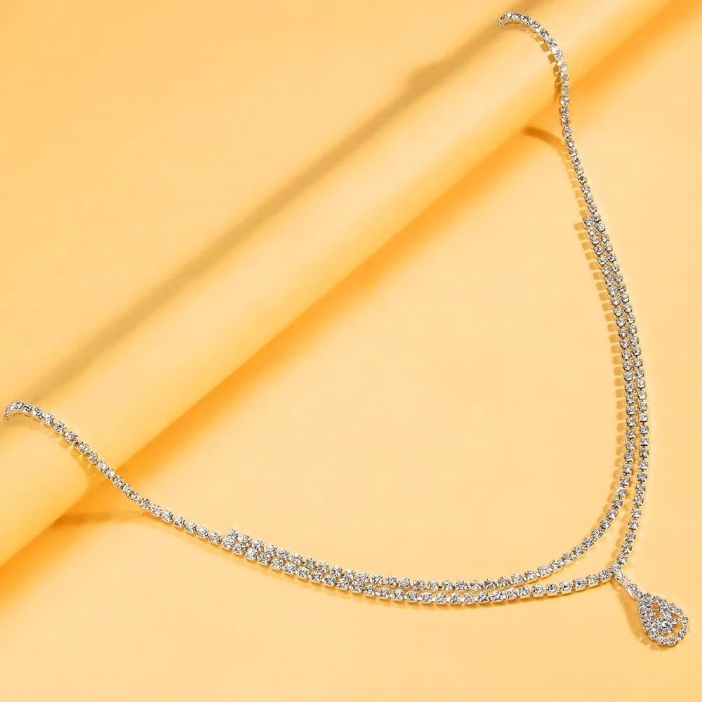 Gold and silver waist chain with a water drop pendant and rhinestone details on a model.