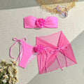 Women's pink tube top swimsuit with a large 3D flower, matching bottoms, and a skirt laid flat.