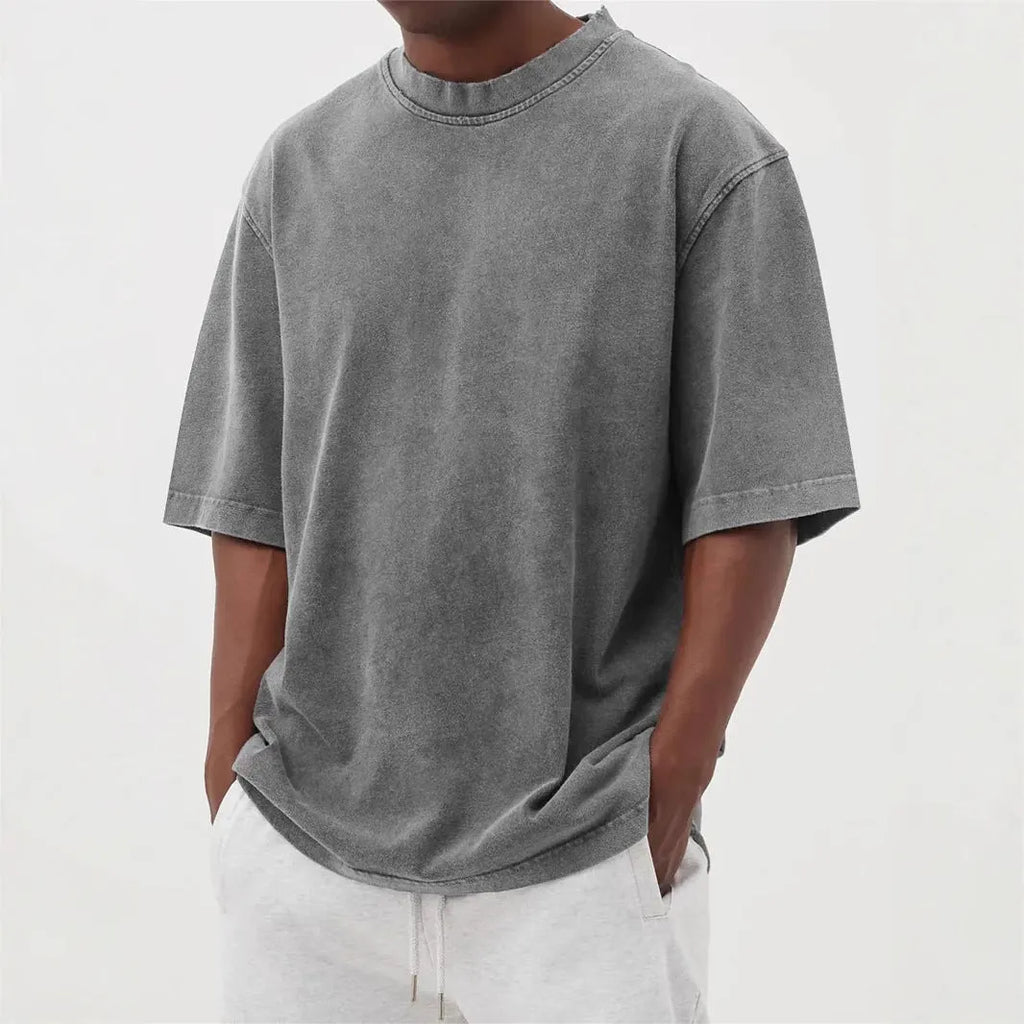 Man wearing a loose-fit, stone-washed distressed men's short sleeve T-shirt in a solid colour.
