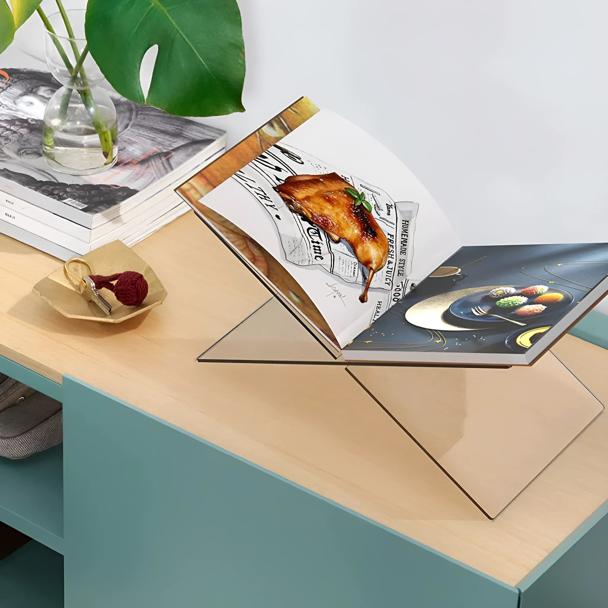 Clear acrylic X-shaped book reading rack holding a book on a desk