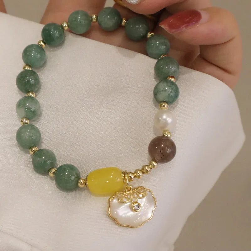Green jade bracelet for women with a metal shell clasp on a wrist.