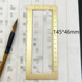Square solid brass calligraphy paperweight with carved scale design on a wooden desk.