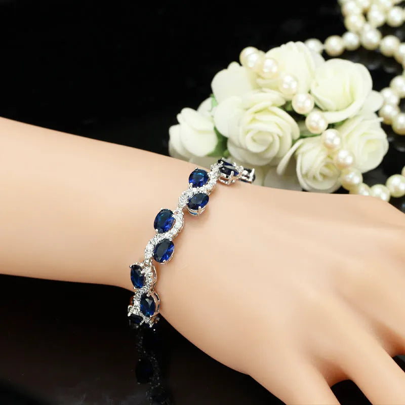 Geometric gold-coloured bracelet with inlaid zircon stones on a white background.