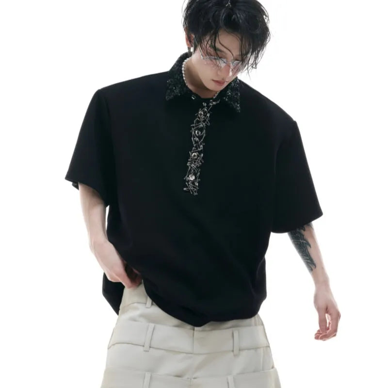 Man wearing a loose fit black polo shirt with a square collar and heavy embroidery sequin detailing on the front