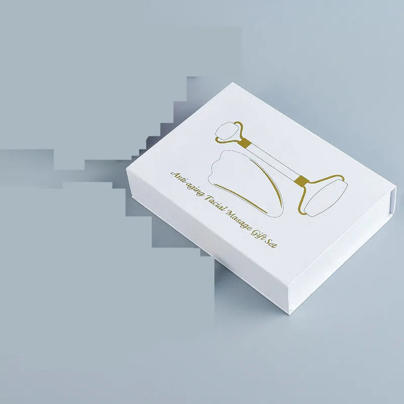 Natural white jade roller and gua sha scraping tool set presented on a wooden storage board.