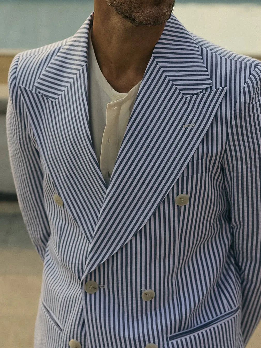 Blue and white striped polyester blazer and trousers suit set on a hanger.