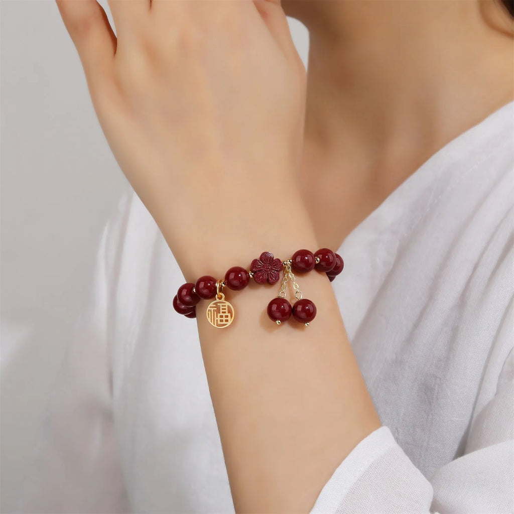 Close-up of a handmade purple gold sand cinnabar bracelet with a Fu character charm and peach blossom tassel.