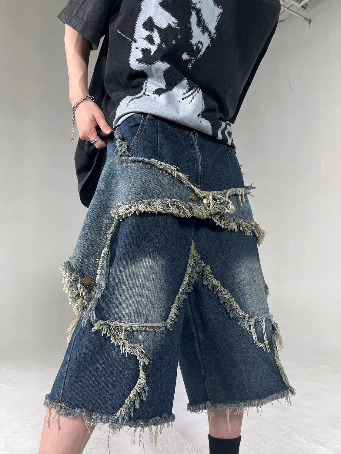 Blue denim shorts with frayed hem and five-pointed star detail, loose fit silhouette