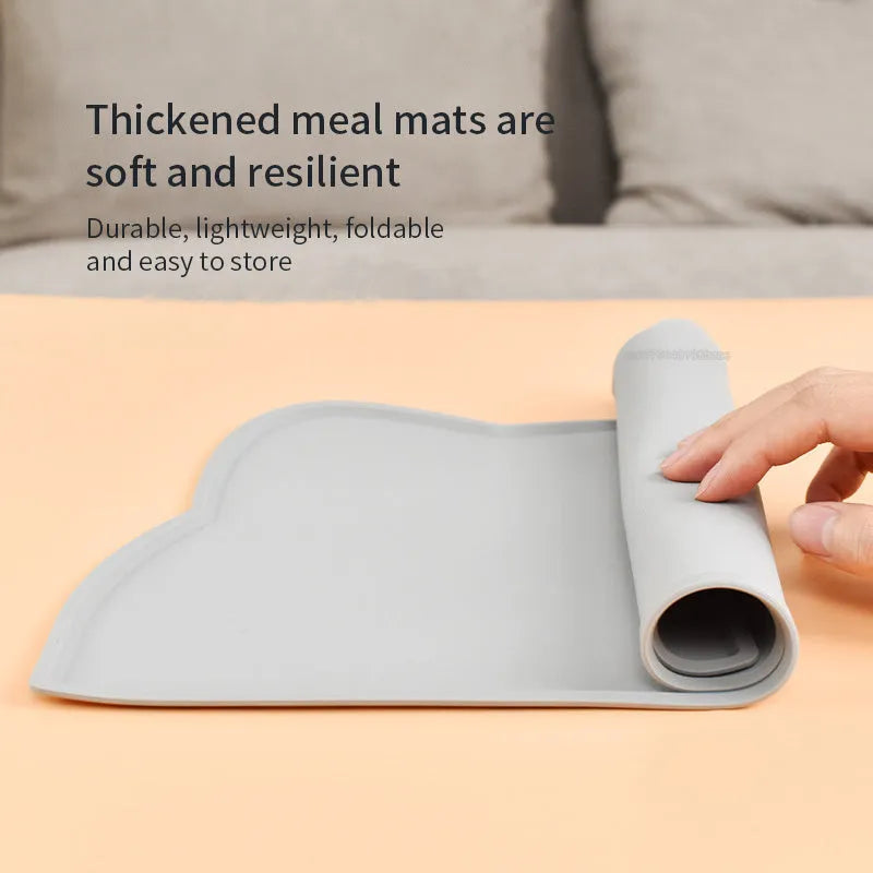 Blue silicone pet feeding mat shaped like a cat head on a wooden floor.