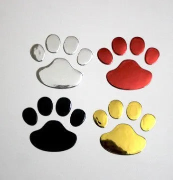 Close-up of a black PVC car sticker with dog footprints and a hand-shaped brush texture on a car bumper.