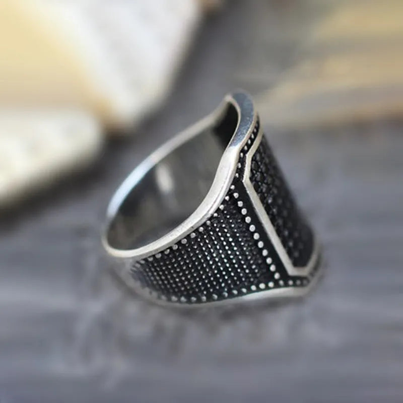 Black alloy ring with copper inlay and zircon stone details, shown on a finger.