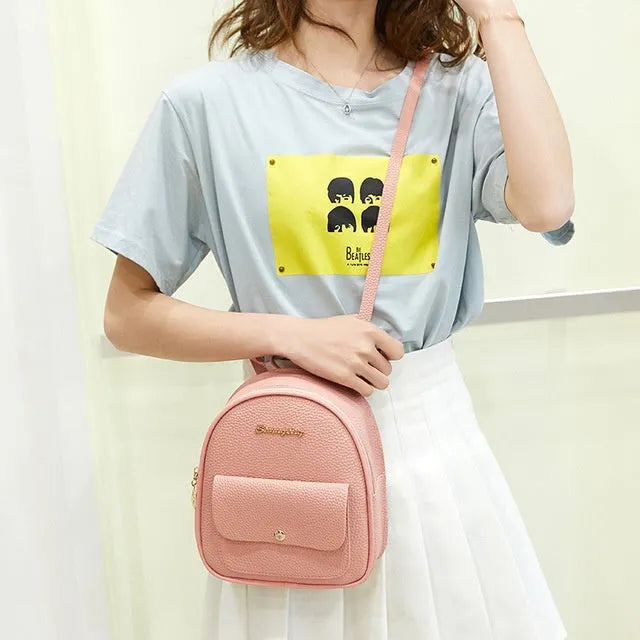 Small black PU leather ladies backpack with zipper, shown on shoulder