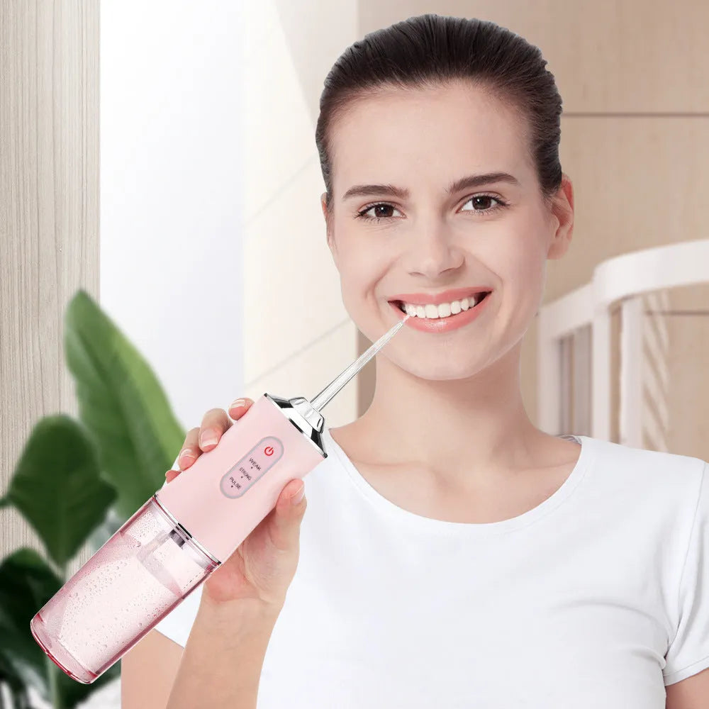 Handheld electric water flosser in white, pink, light green, or white-green with three speed settings, four nozzles, and USB cable