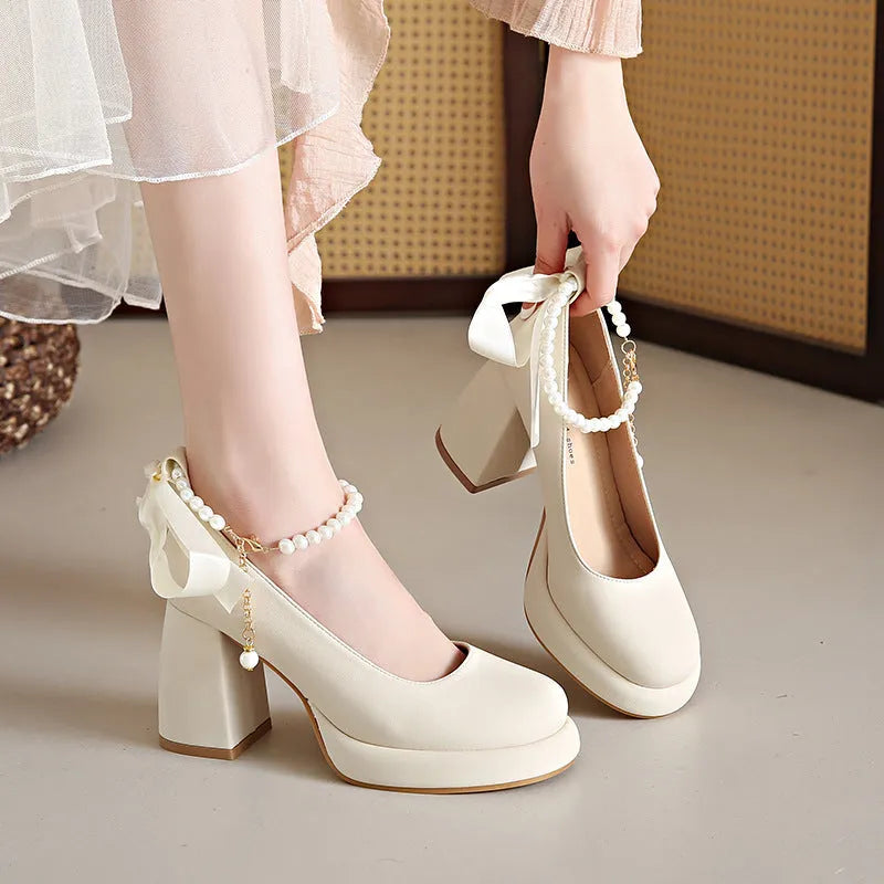 Women's beige Mary Jane shoes with a chunky heel and pearl-embellished ankle-strap buckle on a round toe.