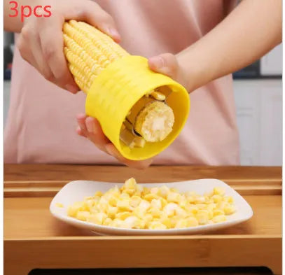Yellow manual corn grinder thresher with corn kernel shaped grip on a kitchen worktop.