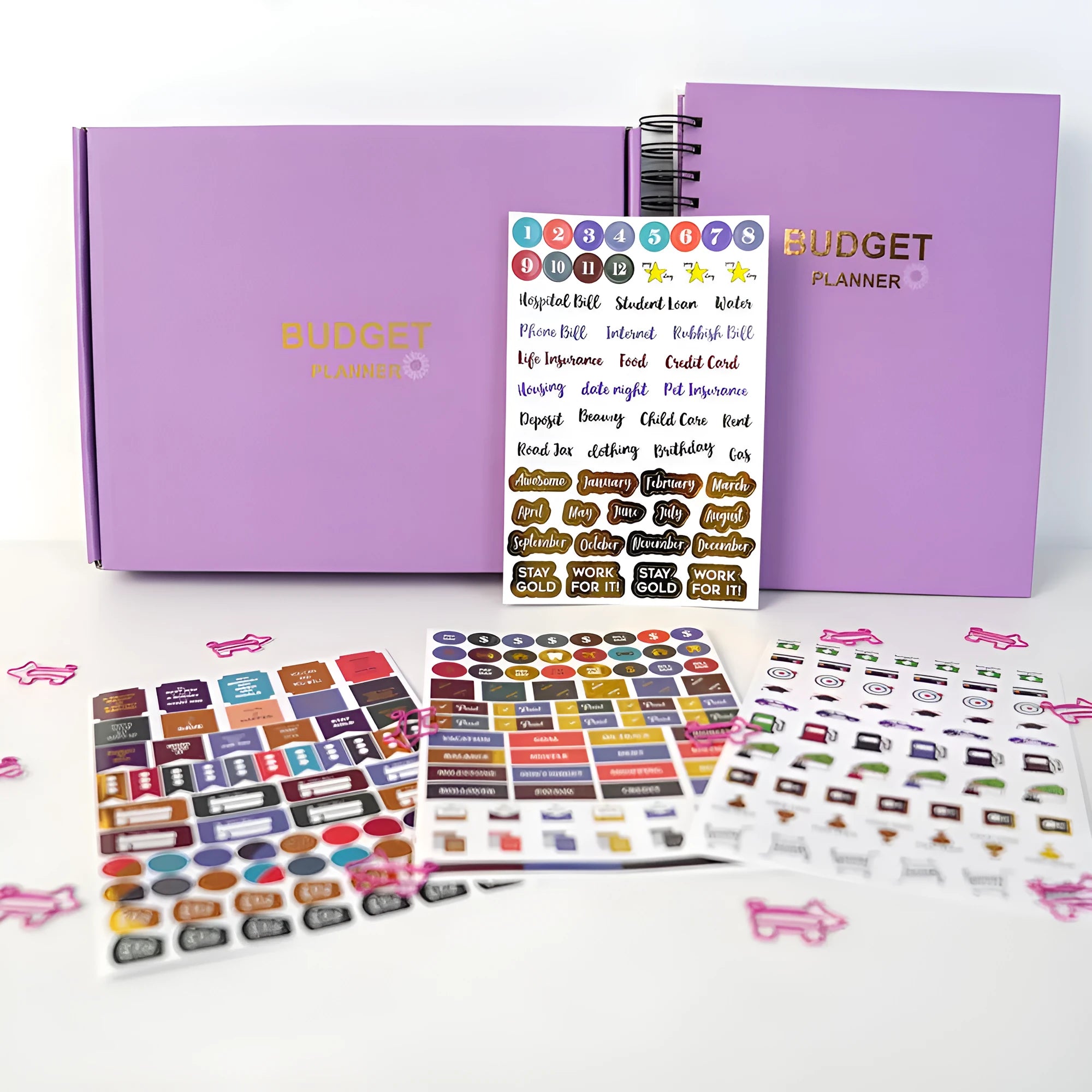 Purple coil-bound financial planning notebook with pen and stickers on a desk.