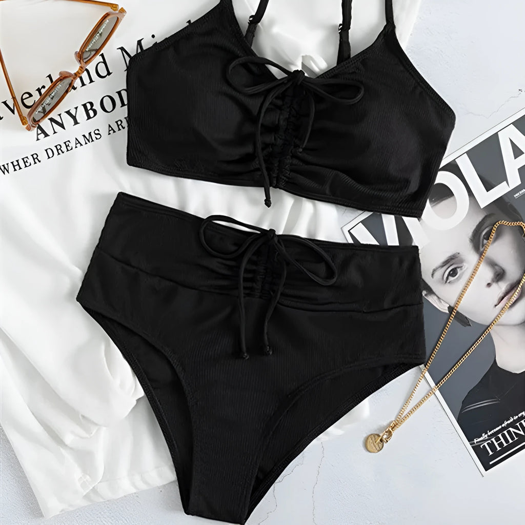 Black women's bikini swimsuit with sling top and high-waisted shorts on a white background
