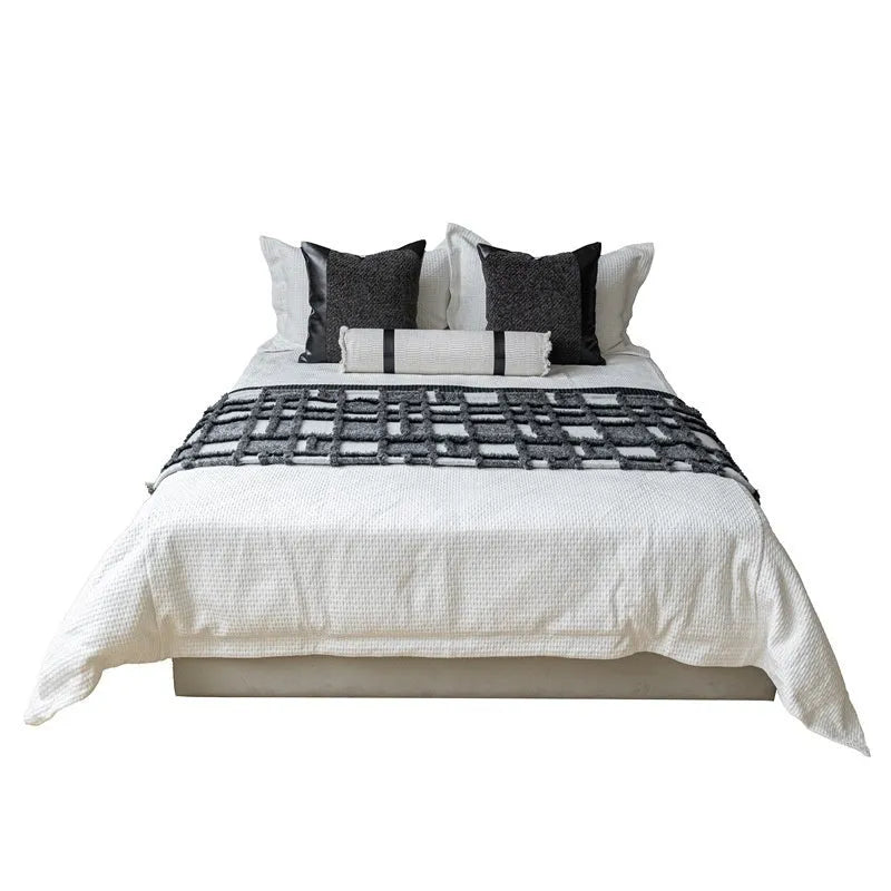 Modern grey and white plaid bed runner blanket set with leather round pillow on a bed