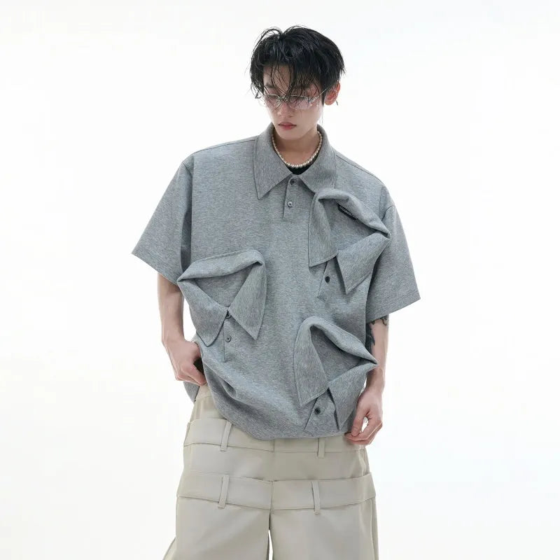 Man wearing a loose-fit black polo shirt with a deconstructed multi-collar and a geometric Giant Land Turtle graphic on the chest.