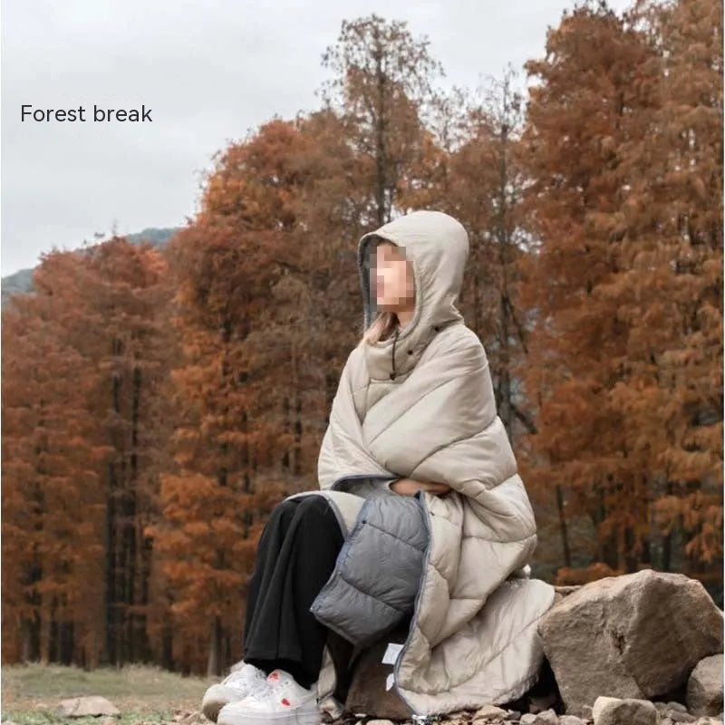 Adult wearing a gray hooded outdoor cloak that converts into a sleeping bag, shown laid flat at 200cm x 140cm.