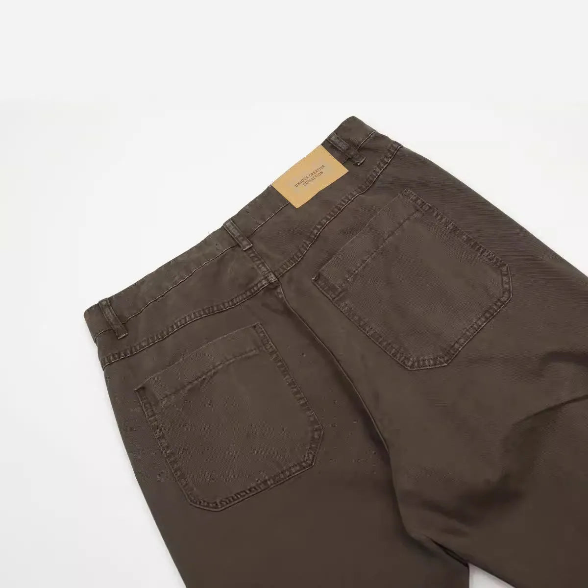 Men's brown straight-leg jeans with high waist and zip fly on mannequin