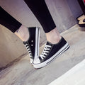 Women's solid-colour canvas shoes in black, shown on a foot from a side angle.