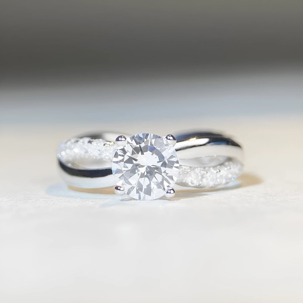 Geometric twisted silver-coloured band moissanite ring with a 1 carat stone in a four-claw setting.