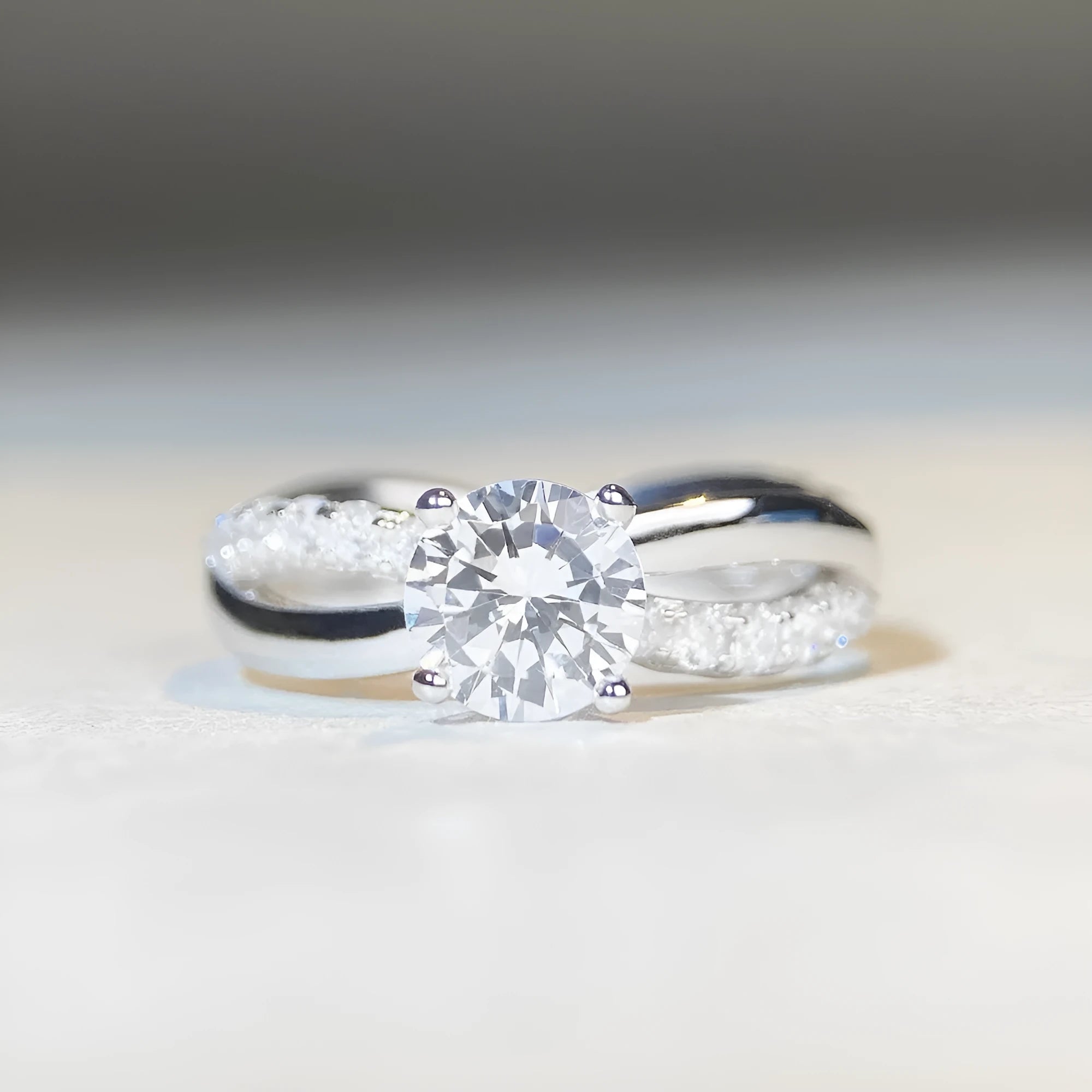 Geometric twisted silver-coloured band moissanite ring with a 1 carat stone in a four-claw setting.