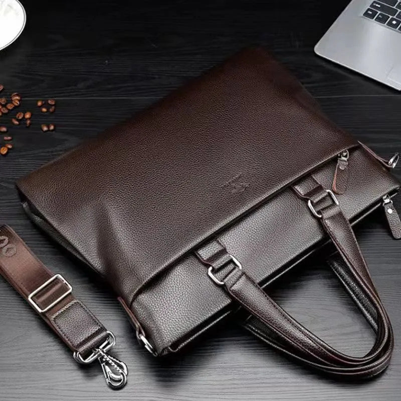 Men's black PU leather shoulder messenger bag with splicing design on a table.
