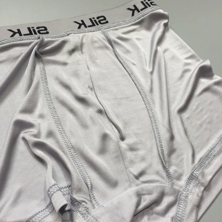 Men's loose-fitting silk shorts in navy blue, shown laid flat to display mid-waist design.