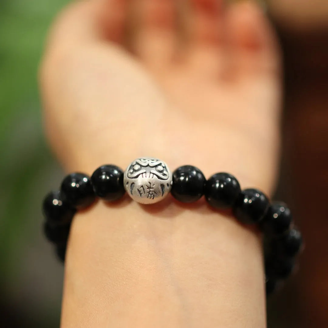 Handmade women's black agate bracelet with 10mm beads and a sterling silver clasp on a wrist.